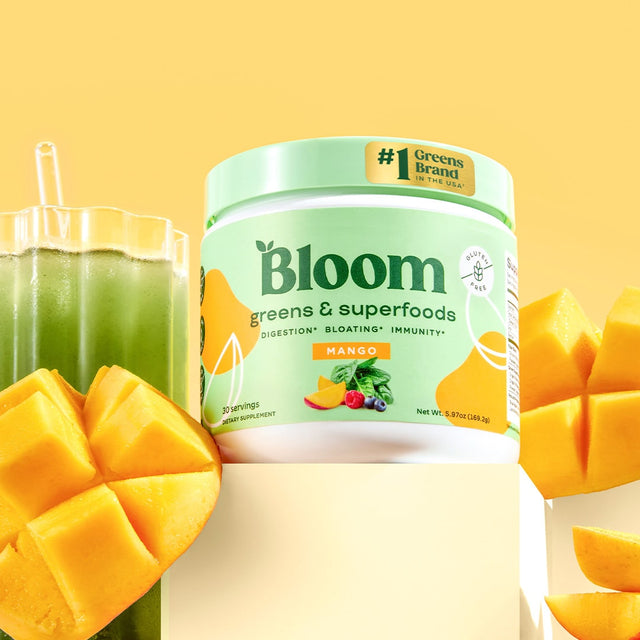 Bloom Greens & Superfoods Mango flavor jar with green drink and fresh mango slices on yellow background