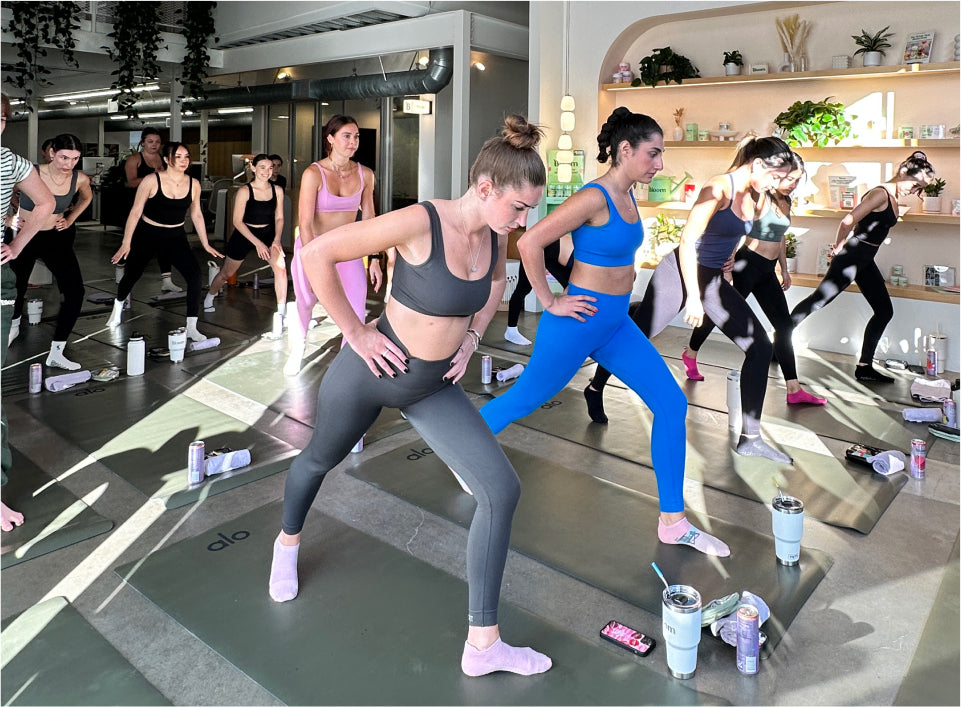 A group of women in activewear are participating in a workout class, focusing on their movements on yoga mats.